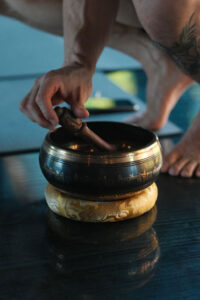 What Is a Sound Bath Session? Sound bowl used during a sound bath session at Namaste Yoga Scottsdale, with a wooden mallet striking a Tibetan singing bowl to create calming vibrations for meditation and relaxation.