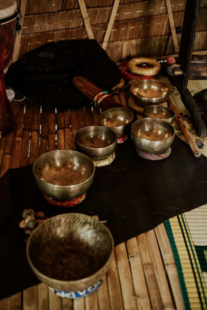 A collection of Tibetan singing bowls arranged on cushions with sound healing instruments used during a sound bath session at Namaste Yoga Scottsdale.