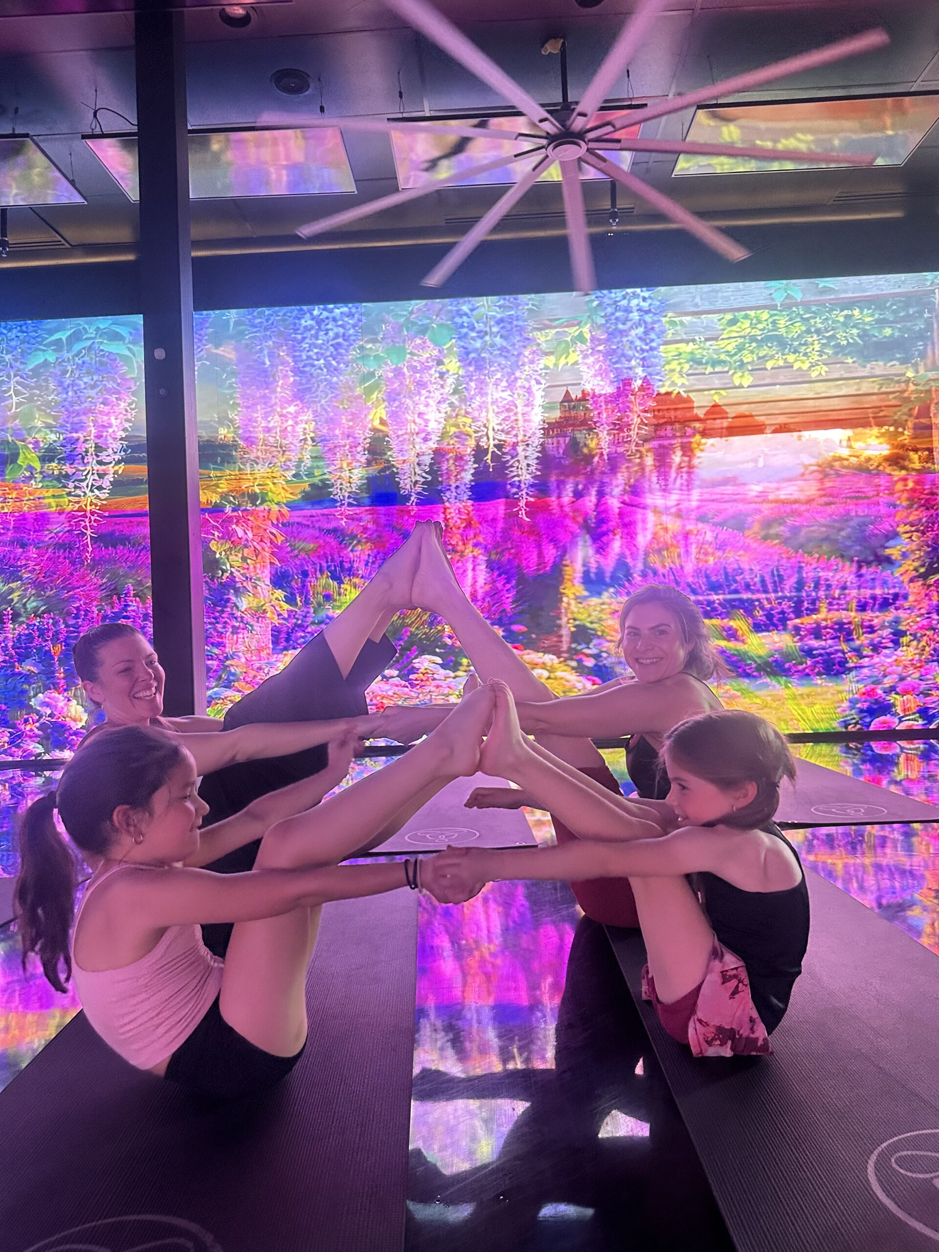 Kids and instructor practicing partner yoga poses in an immersive studio during a yoga camp for kids